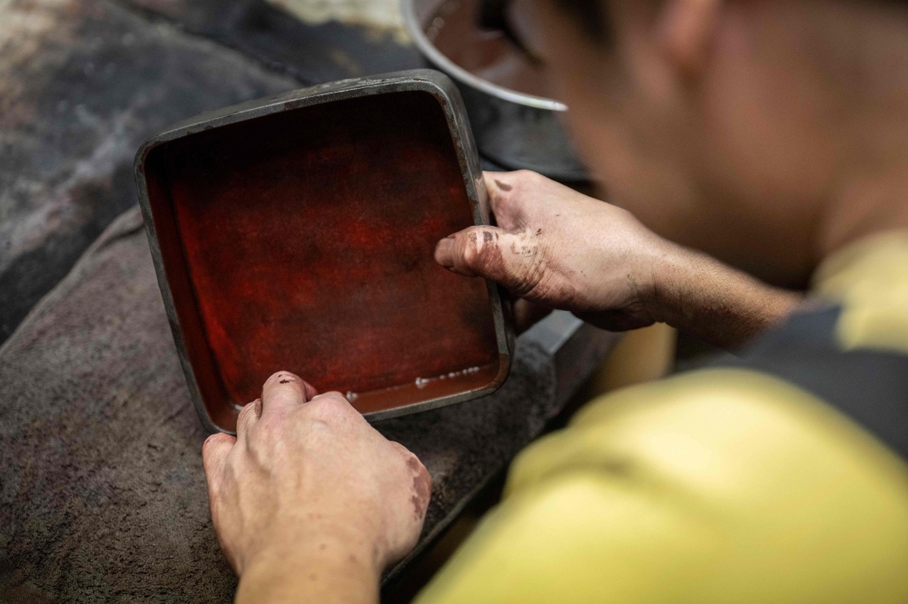 Japanese lacquerware maker Takaho Shoji works at his desk in the Wajima Kirimoto lacquerware studio in Wajima city, Ishikawa prefecture December 11, 2024. — AFP pic