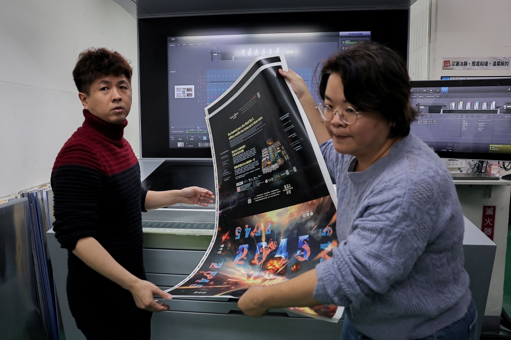 Chang Shao Lian, the founder of Mizo Games, discusses and checks the printing of ‘2045’, a new board game set against the backdrop of armed conflicts around Taiwan, in New Taipei City December 10, 2024. — Reuters pic  