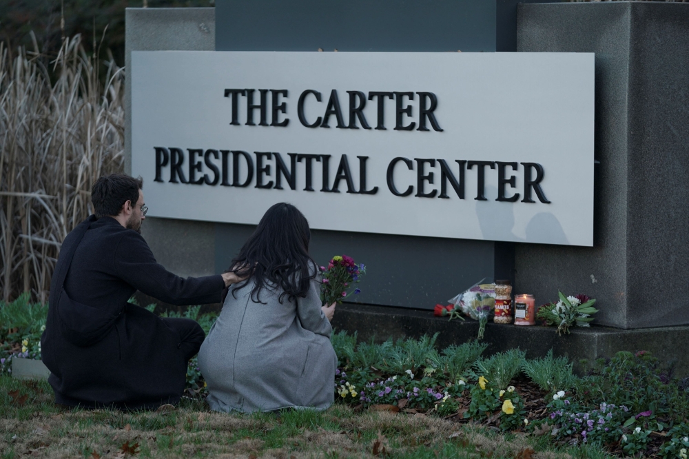 A woman holds flowers in front of The Carter Presidential Center’s sign, after the death of former US President Jimmy Carter at the age of 100, in Atlanta, Georgia December 29, 2024. — Reuters pic