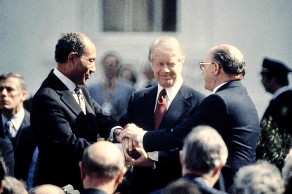 US President Jimmy Carter (centre) congratulates Egyptian President Anwar al-Sadat (left) and Israeli Premier Menachem Begin (right) in three-way handshake on March 26, 1979 on the north lawn of the White House, Washington DC, after signing the historic US-sponsored peace treaty between Israel and Egypt. Carter, the 100-year-old former US president and Nobel peace laureate who rose from humble beginnings in rural Georgia to lead the nation from 1977 to 1981, has died, his nonprofit foundation said on December 29, 2024. — Consolidated News Pictures/AFP pic