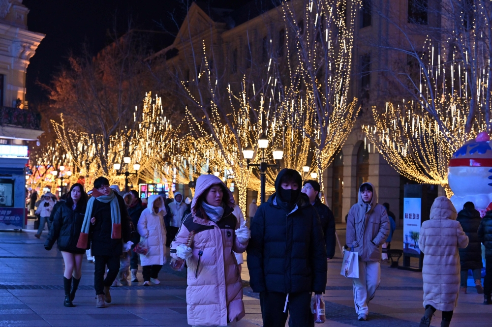 People walking along a street at a tourist centre in Harbin. — AFP pic