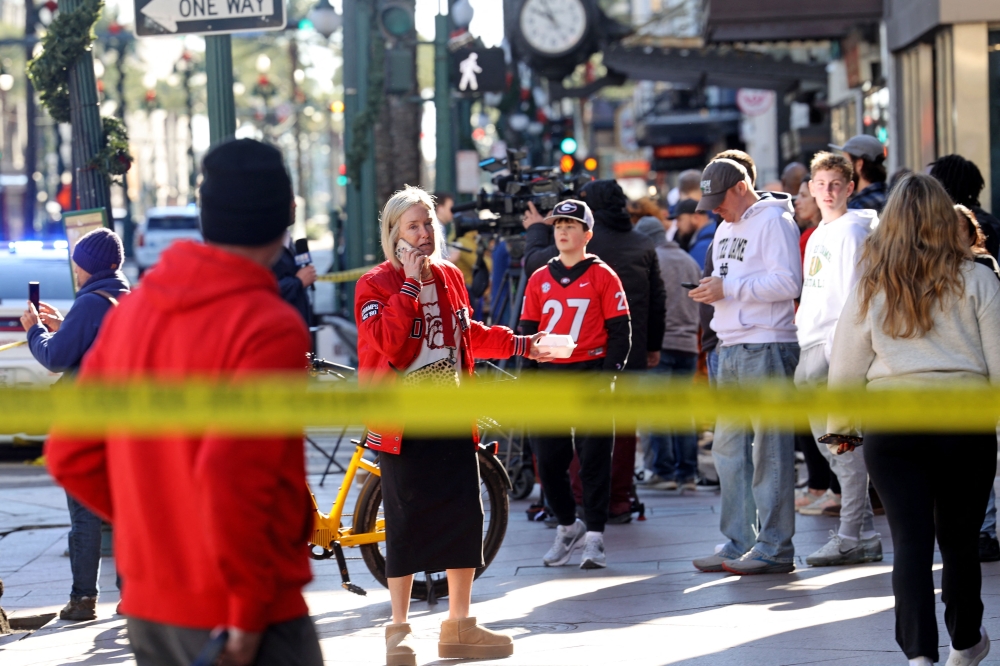 Fans from both Notre Dame and Georgia in town for the now-delayed Sugar Bowl watch the investigation in the French Quarter from Canal Street.— AFP