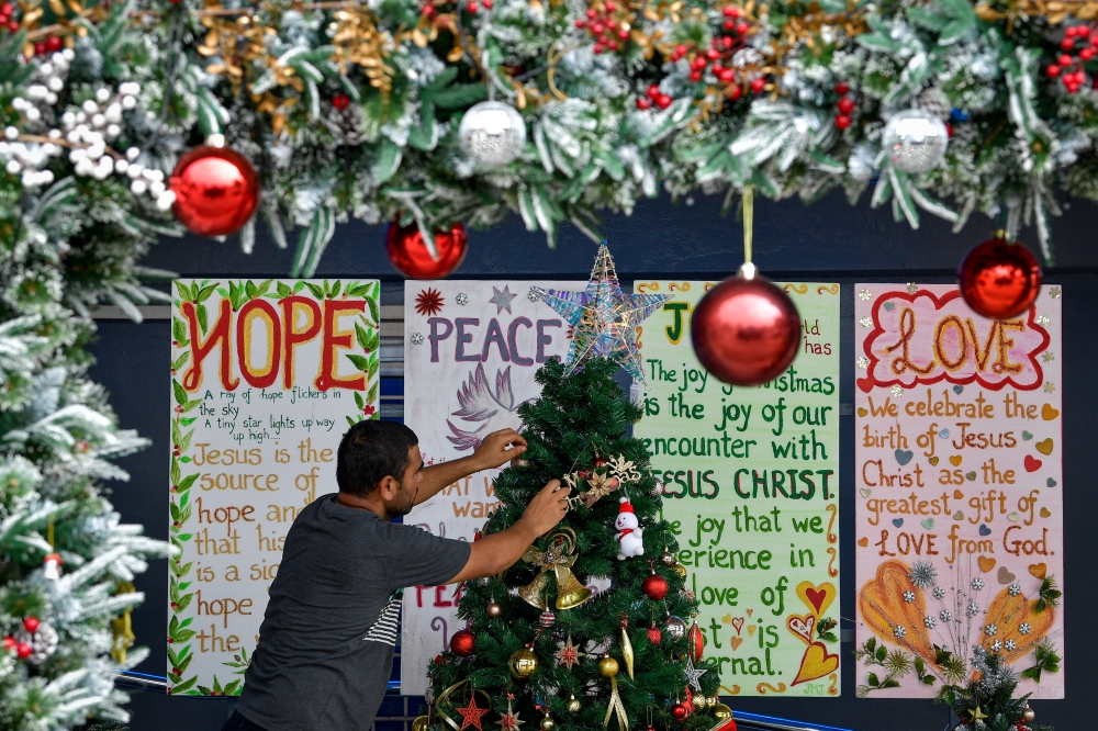 Handwritten messages of hope, peace, joy and love can be seen in the background as a man decorates the Church of Our Lady of Fatima in Brickfields, Kuala Lumpur on December 24, 2024. — Bernama pic