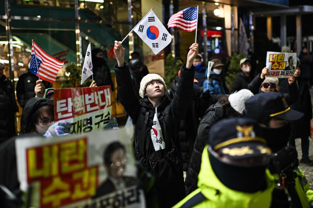 A supporter of South Korea's impeached president Yoon Suk-yeol waves flags of South Korea and the United States near the location where an anti-Yoon rally is taking place in Seoul January 2, 2025. — AFP pic