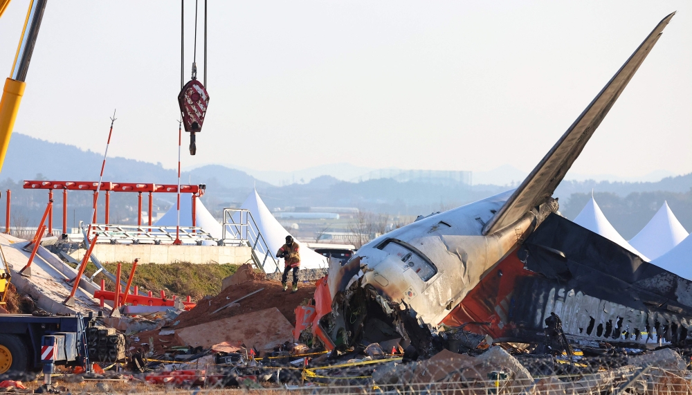 A firefighter takes pictures of the debris at the scene of the Jeju Air passenger plane crash at Muan International Airport in Muan January 3, 2025. — Yonhap/AFP pic