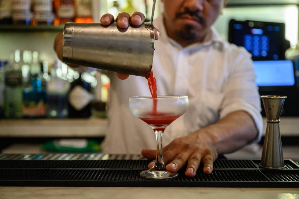 A bartender pours a cocktail at a restarant in New York City on June 13, 2022. The US’ top government doctor on Janauary 3, 2025, called for health warnings on alcoholic drinks to highlight that they cause cancer and urged a reassessment of daily consumption limits due to the risks. — AFP pic