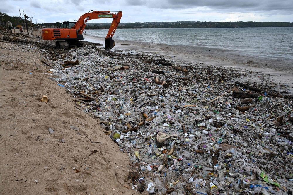 Workers clear plastic waste and other garbage washed ashore that has accumulated thickly at a beach in Kedonganan Badung regency, on the resort island of Bali on January 3, 2025. — AFP pic