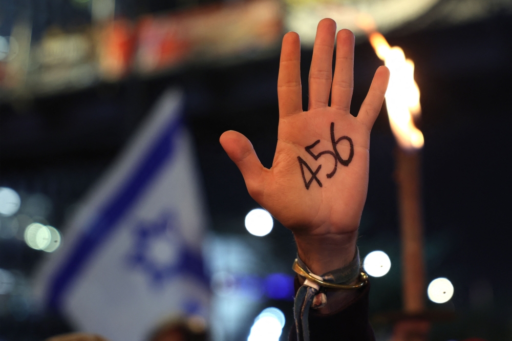 A Protester shows her palm with the number of days Israel is at war. — AFP