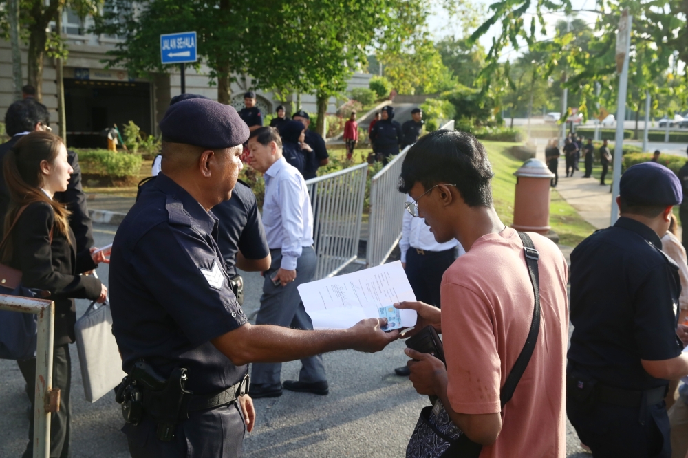 A policeman screens people entering the vicinity of the Palace of Justice in Putrajaya during a solidarity rally for convicted former prime minister Datuk Seri Najib Razak who is appealing against the dismissal to serve the remainder of his six-year prison sentence under ‘house arrest’ on January 6, 2025. — Picture by Choo Choy May