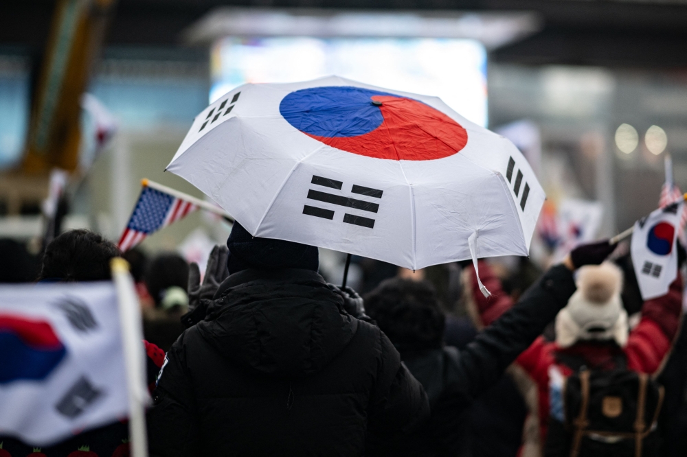 A supporter of impeached South Korean president Yoon Suk Yeol holding an umbrella with the South Korean flag. — AFP