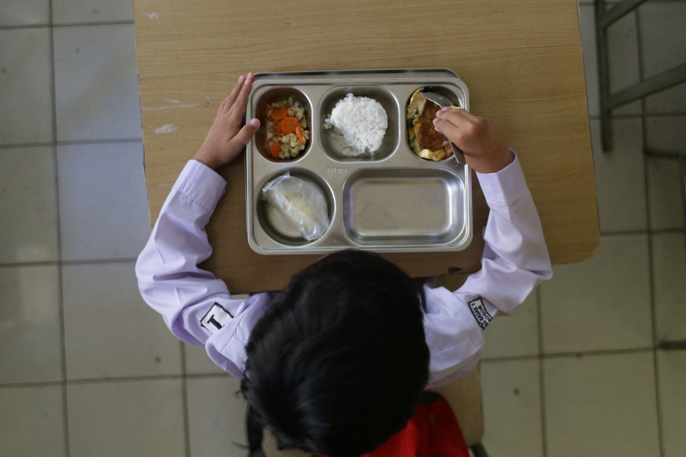 A student eats lunch on the first day of a free-meal programme. — AFP