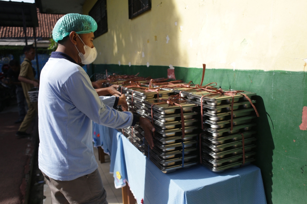 A staff member prepares lunch plates to deliver. — AFP