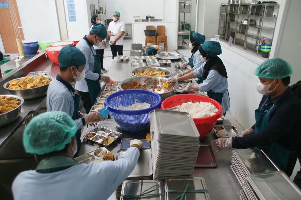 Staff prepare lunch plates on the first day of a free-meal program at a public kitchen. — AFP