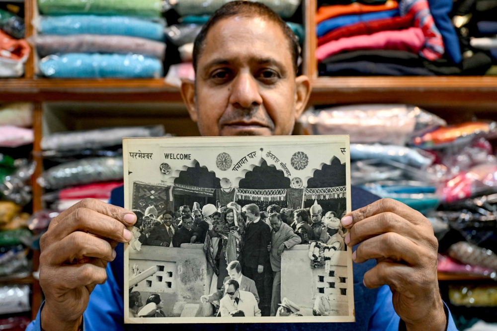 Resident Rajiv Kumar shows a photograph at his shop near Carterpuri village in Gurgaon on January 7, 2025, picturing late former US president Jimmy Carter (centre) and his wife Eleanor Rosalynn Carter (centre left) during their visit to the eponymous village in 1978. — AFP pic