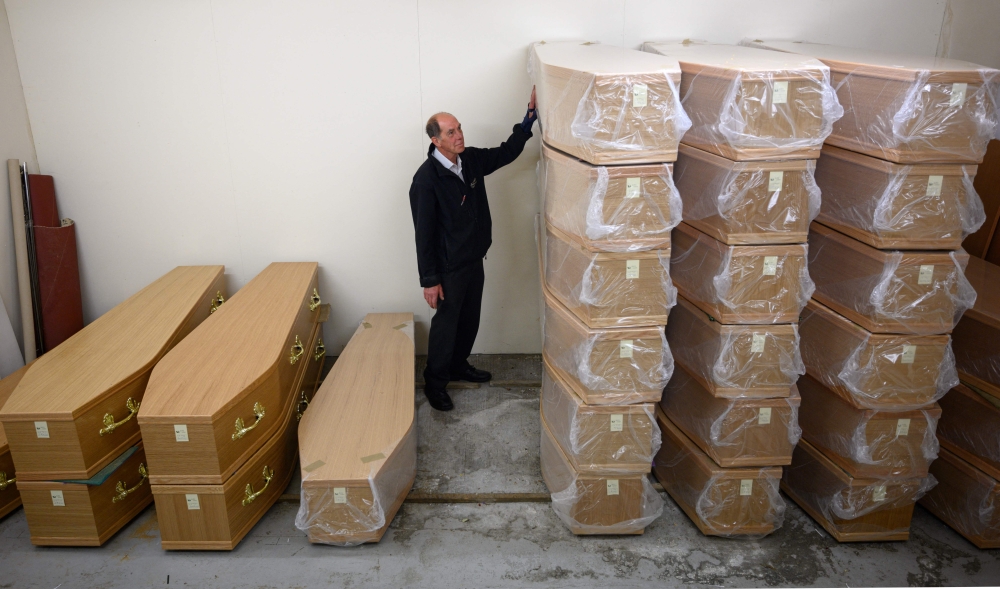 Funeral service operative Howard Jackson prepares to move a coffin from their storeroom at their funeral home in Manchester, northern England on May 26, 2020. — AFP pic