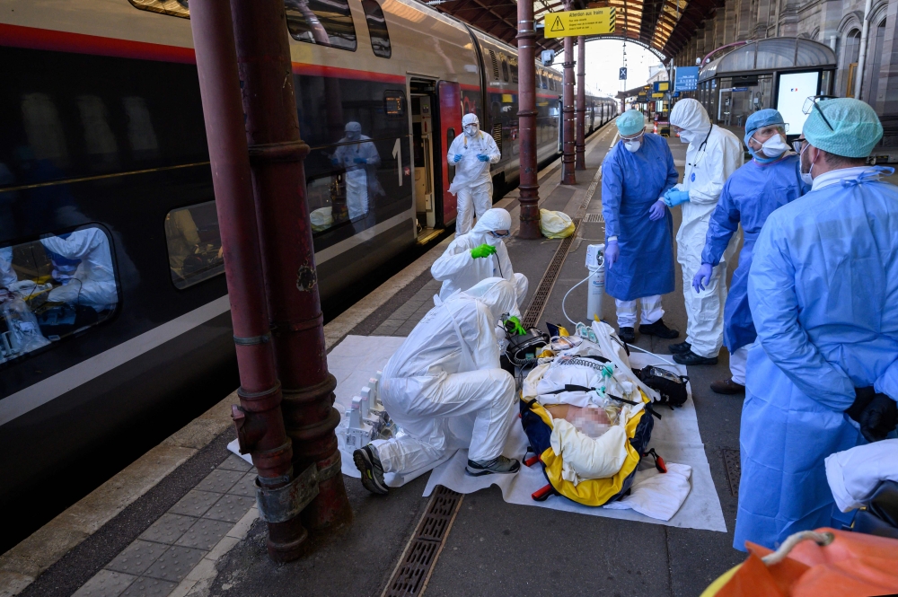 Medical staff carry a patient infected with the COVID-19 onboard a medicalized TGV high speed train at the railway station in Strasbourg, eastern France, on April 3, 2020. — AFP pic