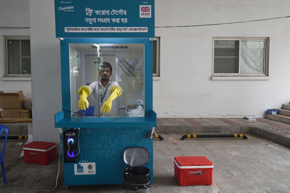 An employee of the Mugda Medical College and Hospital waits to conduct a swab sample test of a resident for the COVID-19 coronavirus, in Dhaka on June 17, 2020. — AFP pic