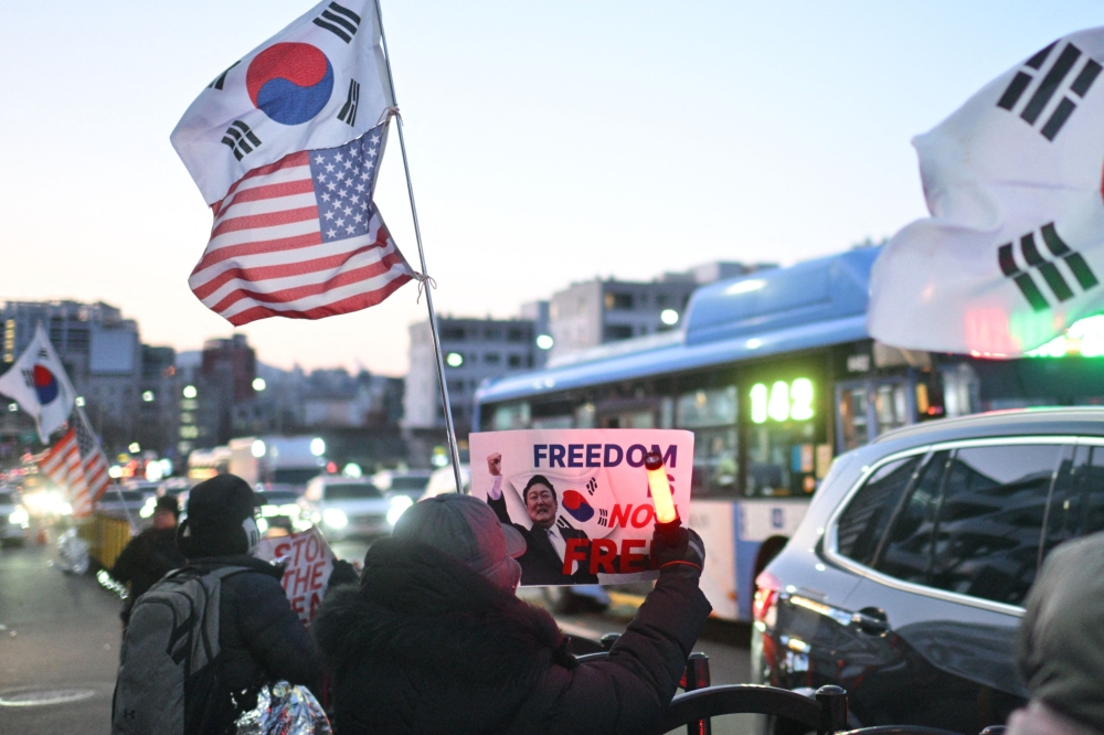 Supporters of impeached South Korean president Yoon Suk-yeol display signs towards commuters driving past the rally near his residence Seoul January 9, 2025. — AFP pic