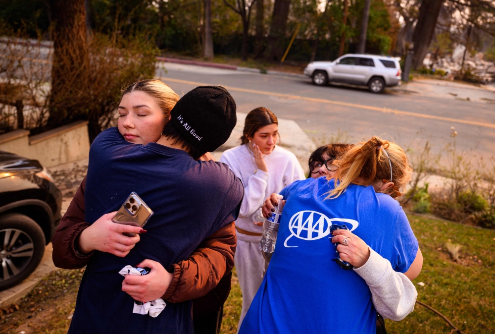 A family cries while embracing as they arrive at their burned home. — AFP