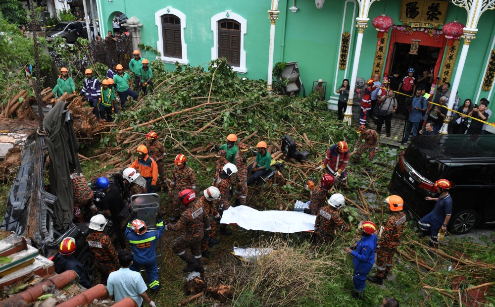 Fire and Rescue Department personnel remove the body of one of the two foreign victims who died after their car was crushed by a fallen tree on Lebuh Gereja in George Town, September 18, 2024. — Bernama pic