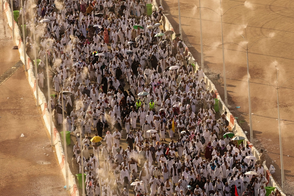 Muslim pilgrims walk under mist dispensers as they arrive to perform the symbolic 'stoning of the devil' ritual during the annual hajj pilgrimage in Mina on June 16, 2024. — AFP pic