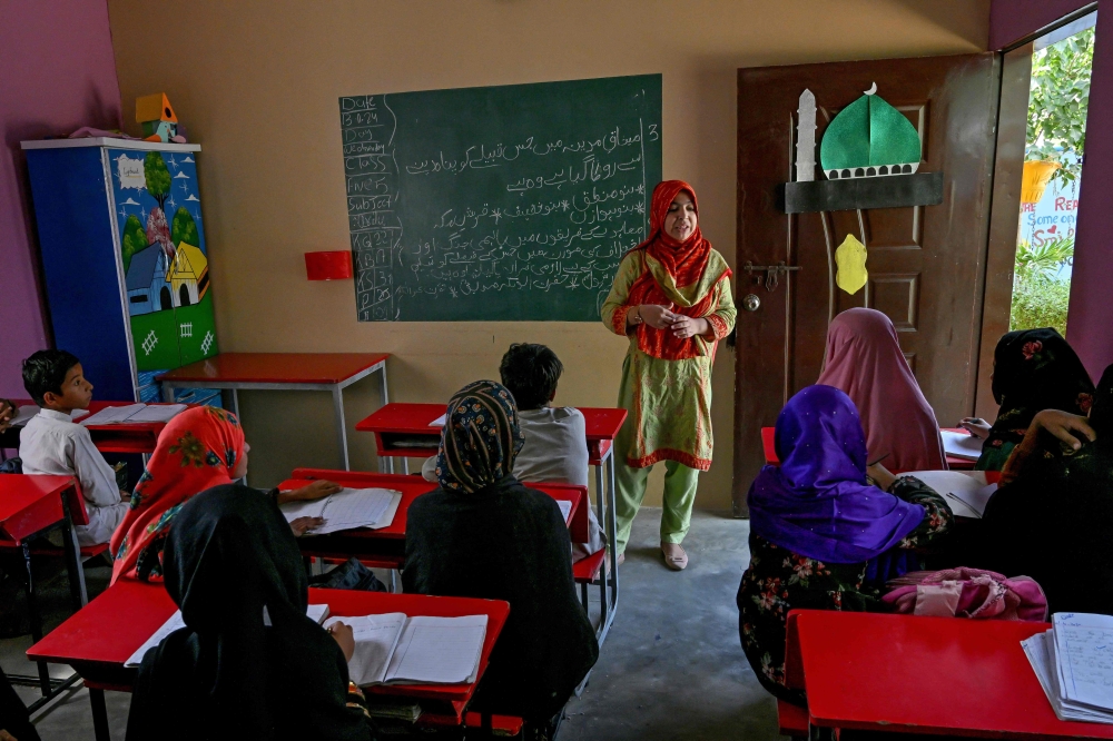 Rukhsar Amna, a 27-year-old school principal, interacts with children at a community school in Abdullah Goth village on the outskirts of Karachi November 13, 2024. — AFP pic