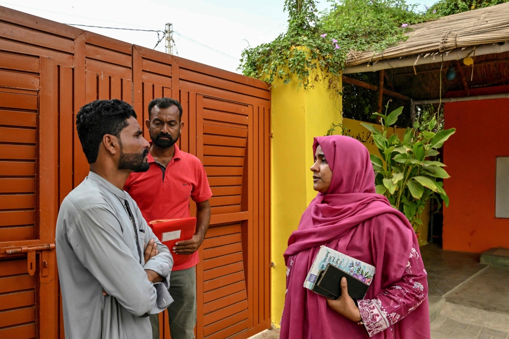 Humaira Bachal (right), a 36-year-old education advocate from the Roshan Pakistan Foundation School, speaks with parent at a community school in Abdullah Goth village on the outskirts of Karachi November 13, 2024. — AFP pic