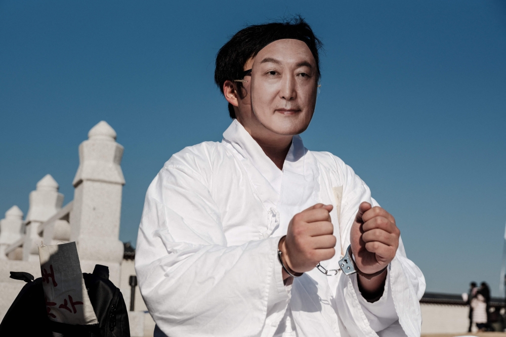 A protester wears a mask of impeached South Korean President Yoon Suk Yeol before the start of the rally. — AFP