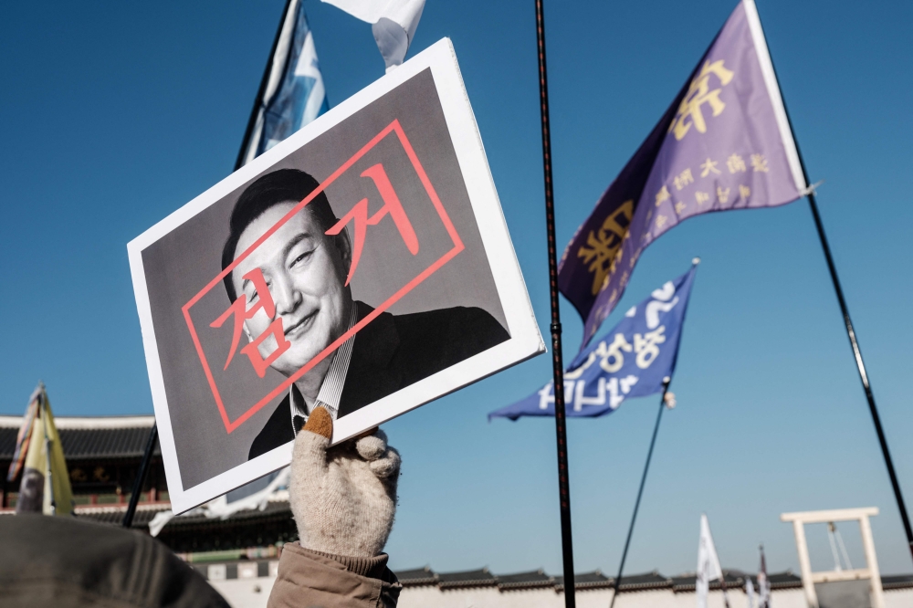 A protester walks with a portrait of impeached South Korean President Yoon Suk Yeol. — AFP