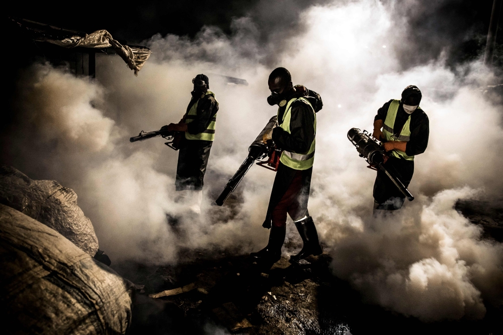 Members of a privately-funded NGO working with county officials wearing protective gear fumigate and disinfect on April 15, 2020. — AFP