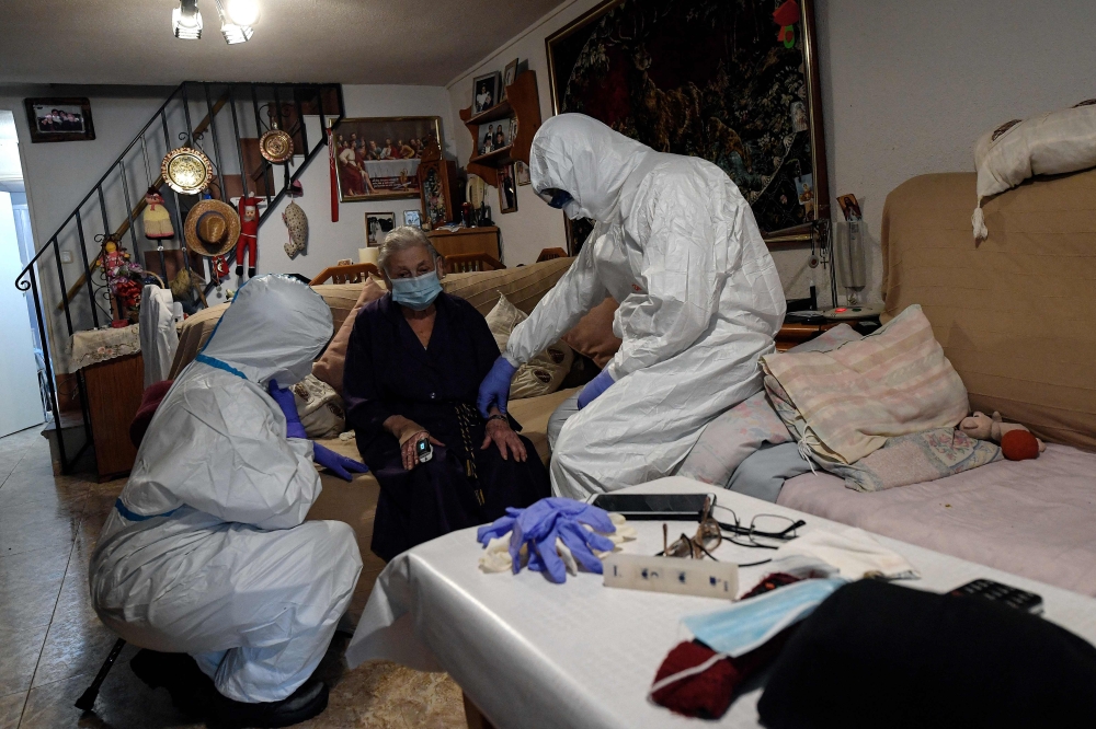 Medical Emergency Services of Madrid (SUMMA 112) UVI-6 unit wearing protective suits examine a suspected COVID-19 patient Asuncion at her home in Madrid on April 19, 2020. — AFP