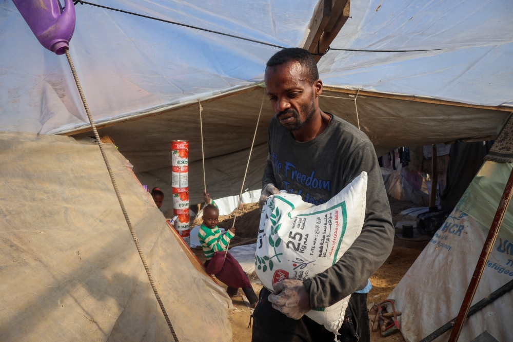 Tayseer Obaid prepares to dig a trench in his tent in an attempt to protect his children from the cold and Israeli strikes, in a makeshift camp in Deir el-Balah January 8, 2025. — AFP pic