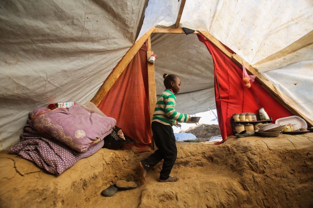 A Palestinian girl exits a tent where her father Tayseer Obaid dug a trench in an attempt to protect his children from the cold and Israeli strikes, in a makeshift camp in Deir el-Balah January 8, 2025. — AFP pic