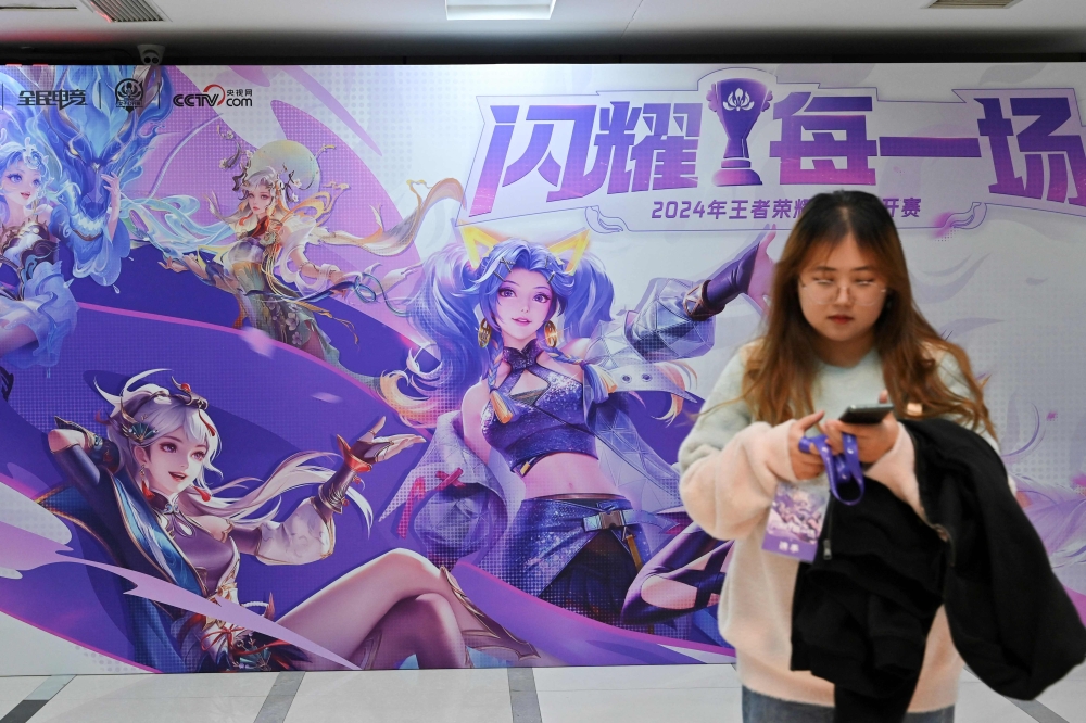 A woman stands next to a large picture featuring an esport event in Beijing December 19, 2024. — AFP pic