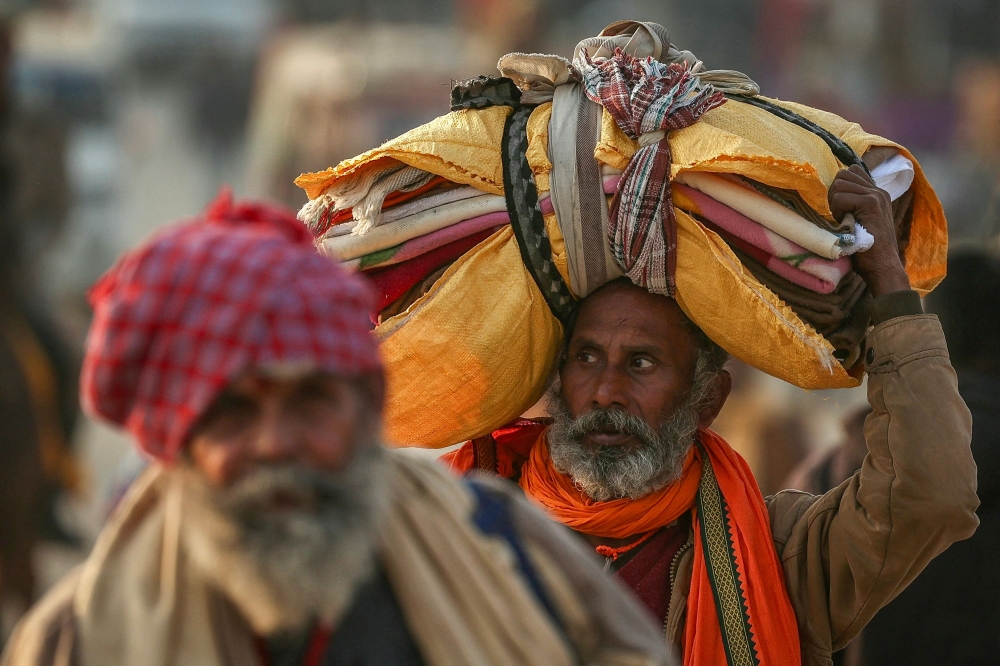 Hindu pilgrims carrying their belongings arrive at Sangam, the confluence of Ganges, Yamuna and mythical Saraswati rivers, ahead of the Maha Kumbh Mela festival in Prayagraj January 11, 2025. — AFP pic