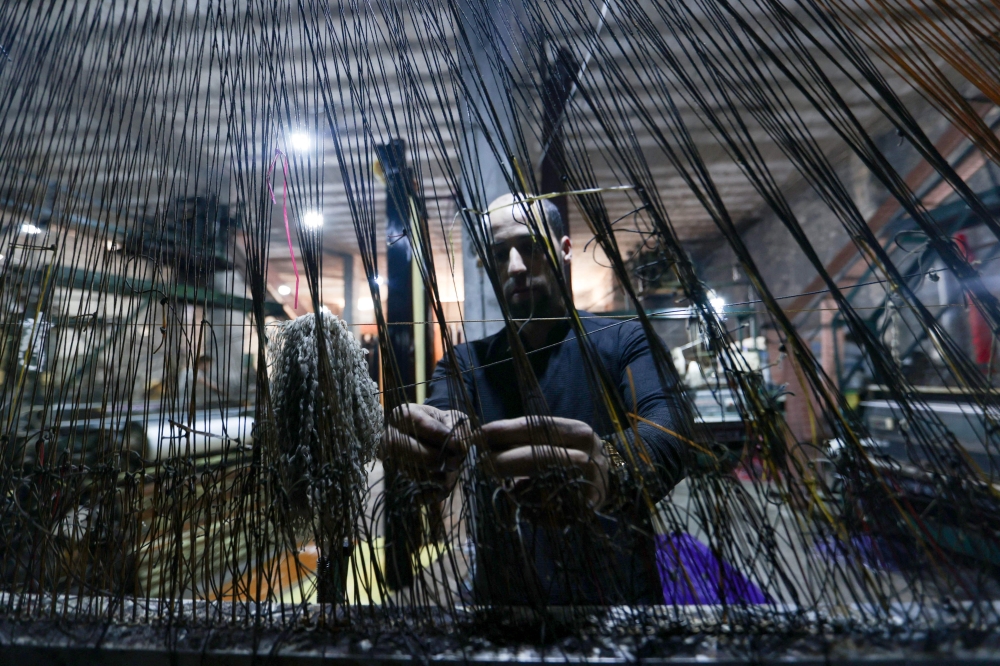 A man works at a factory making mats and rugs from recycled plastic, in Sarmada, Syria. — AFP pic 