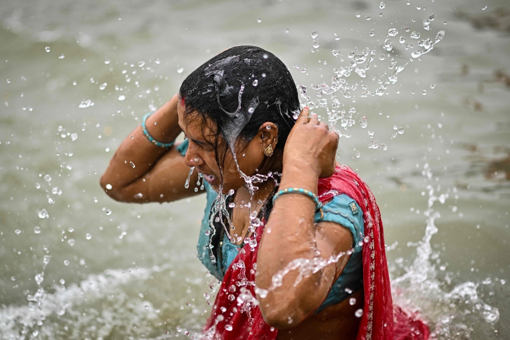 A Hindu pilgrim takes a holy dip in the sacred waters of Sangam. — AFP pic