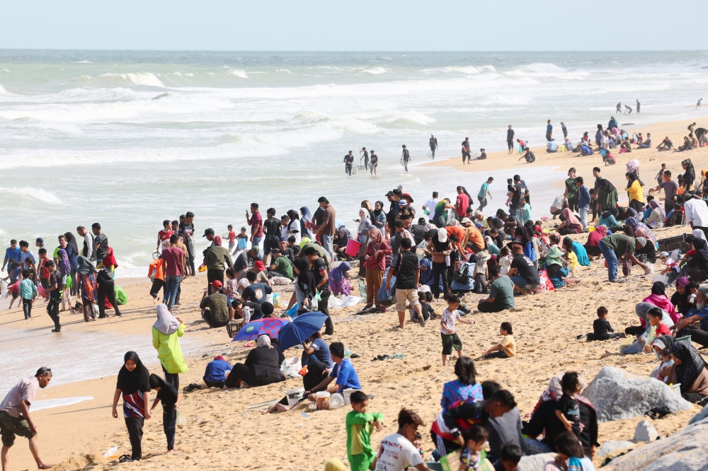 People collect cockles that were washed ashore following large waves that hit Sura Beach January 15, 2025. — Bernama pic