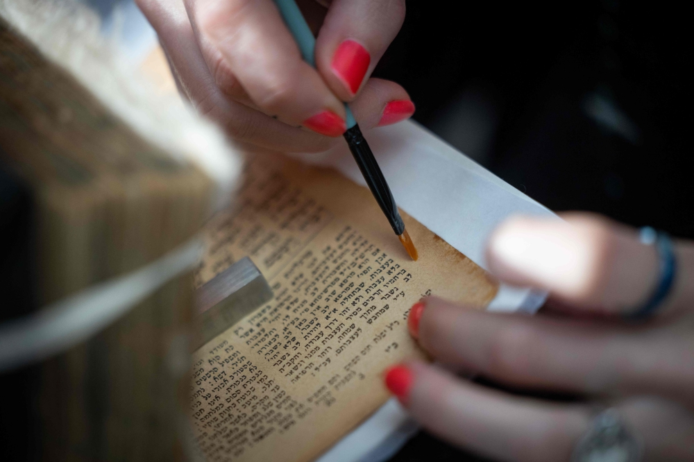 A worker works on the preservation of a Hebrew book – part of the possessions confiscated from the victims of the former Nazi concentration and extermination camp, in Oswiecim, Poland, on January 14, 2025. — AFP pic