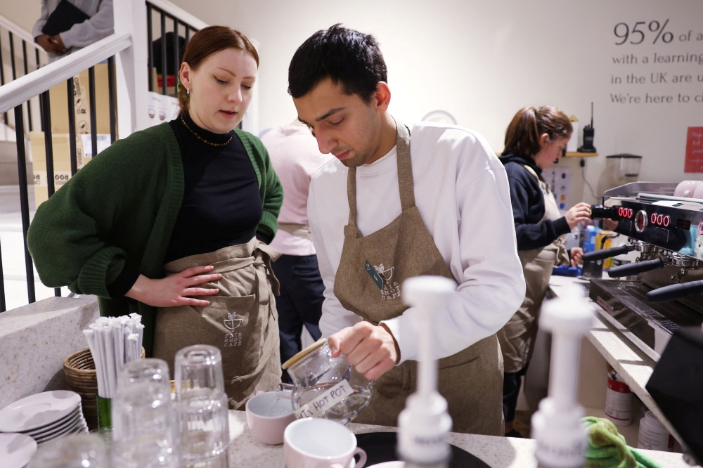 Trainer Anna watches learner Zaki as they work in Fair Shot, a cafe set up to train young people with autism and other learning disabilities in employment skills, in central London, Britain, January 15, 2025. — Reuters pic