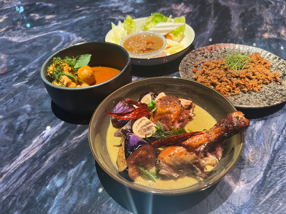 The menu at Sood features Thai-inspired dishes (clockwise from top) such as simmered coconut with fermented bean and prawn served with fresh vegetables, stir-fried minced beef with ginger curry, green curry with grilled chicken and red curry with minced fish. 