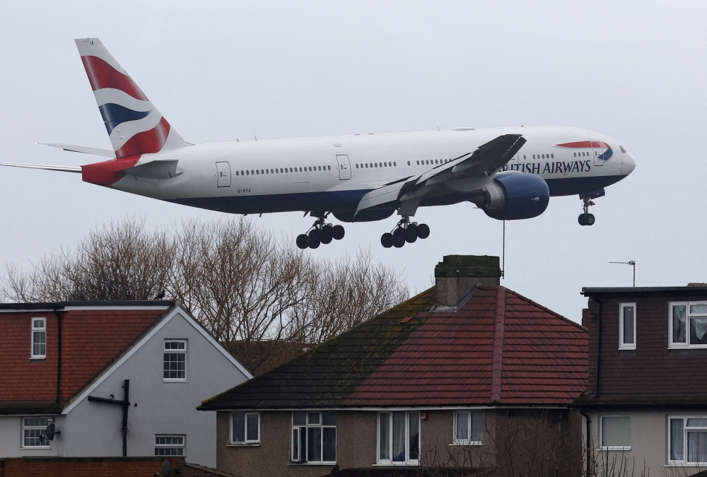 A British Airways passenger plane flies near houses as it makes its landing approach to Heathrow Airport. — Reuters pic