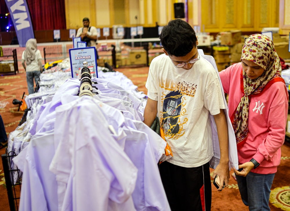 A mother helps her son select his uniform at the Rahmah Sales and Back-to-School Programme in Putrajaya February 16, 2025. — Bernama pic