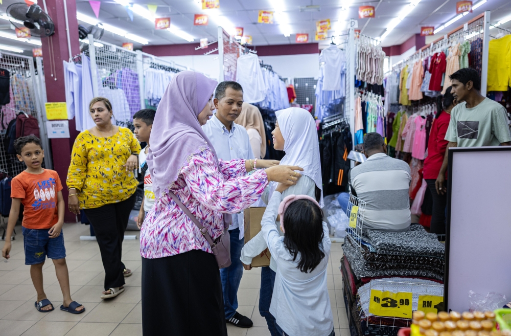 A mother adjusts a headscarf for her daughter, while making last-minute school supply purchases in Ipoh February 16, 2025. — Bernama pic