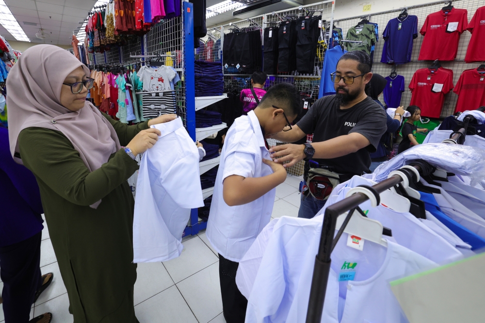 Parents help their son pick out a new school uniform in preparation for the start of the 2025/2026 school session tomorrow in Johor Baru February 16, 2025. — Bernama pic