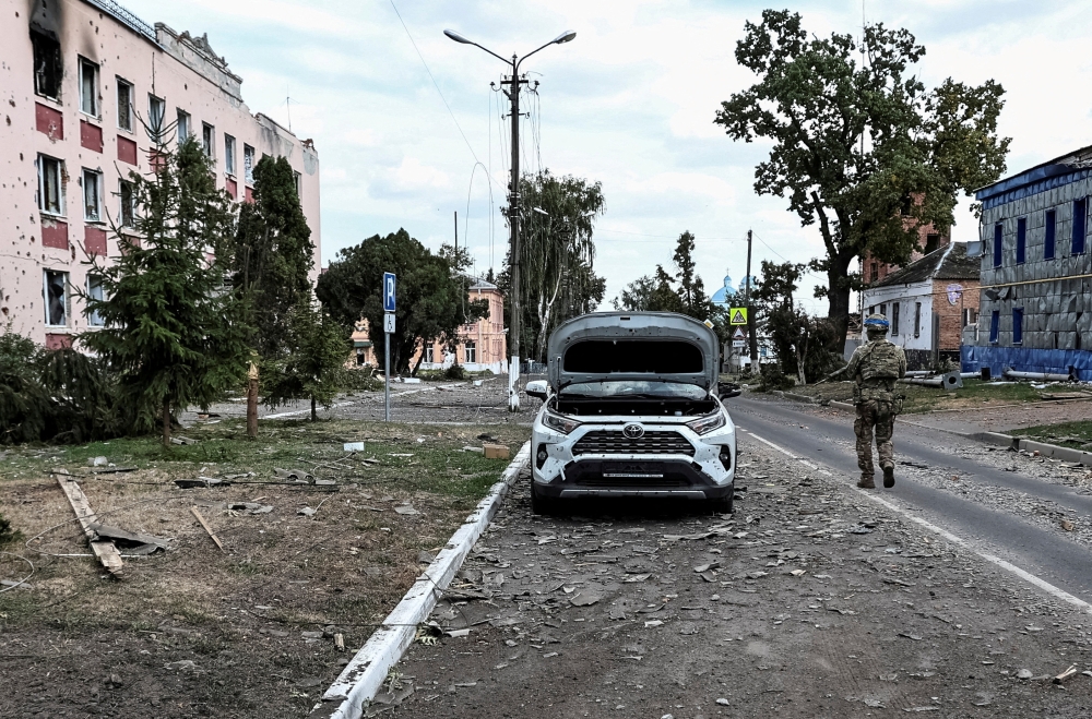 ウクライナ戦争 2024年8月16日、ロシアのクルスク地方にあるウクライナ軍支配下の町スジャで、ウクライナ軍とロシア軍の戦闘で破損した建物の横をパトロールするウクライナ軍兵士。- ロイター写真 