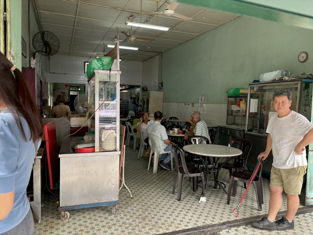 Kedai Kopi Sin Yoon Loong owner Wong Kee Chor stands at the entrances of his coffee shop in Ipoh. — Picture by John Bunyan