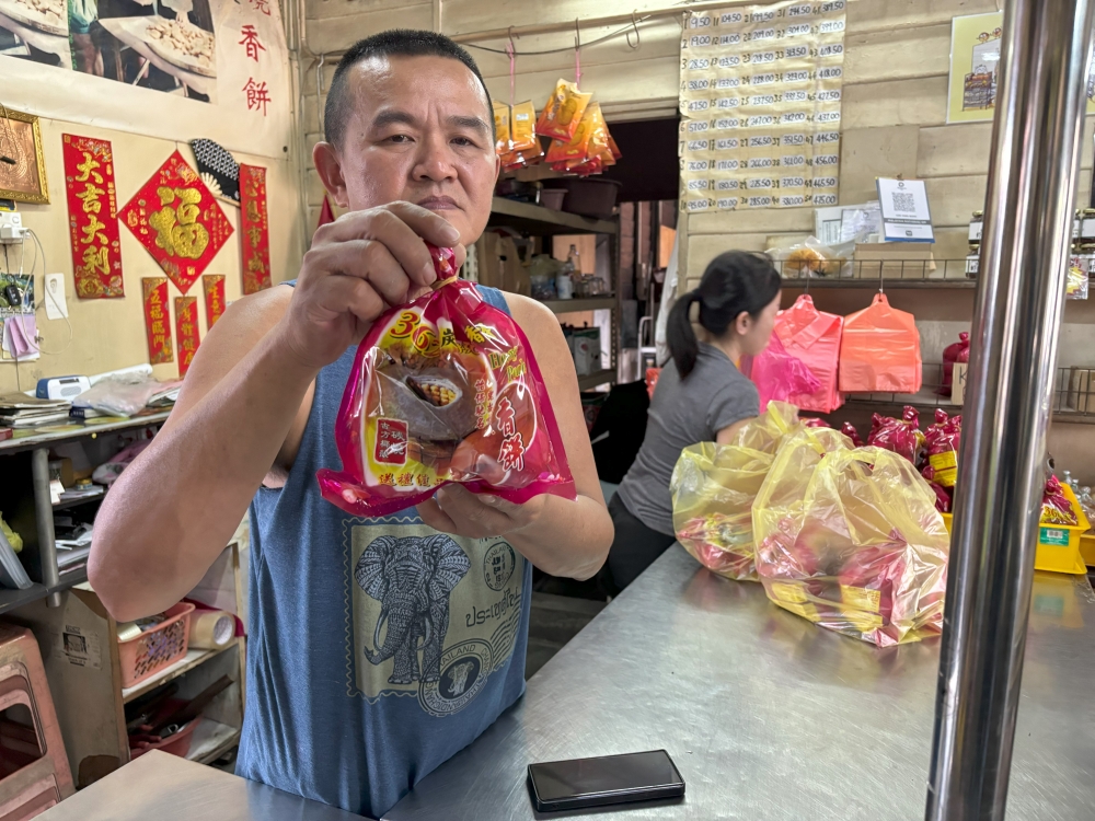 Keong Kee Heong Peng owner Lew Yung Voon holds up a bag of heong peah at his shop in Ipoh. — Picture by John Bunyan