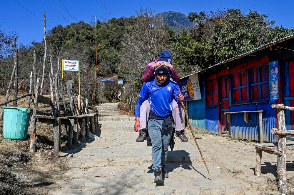 A porter carrying a devotee on his back hikes to the Pathibhara Devi temple. — AFP pic