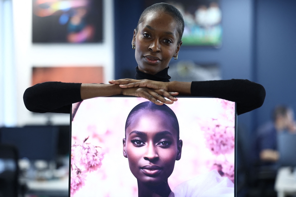 London-based model Alexsandrah Gondora poses for a photograph with her on-screen AI twin. — AFP pic